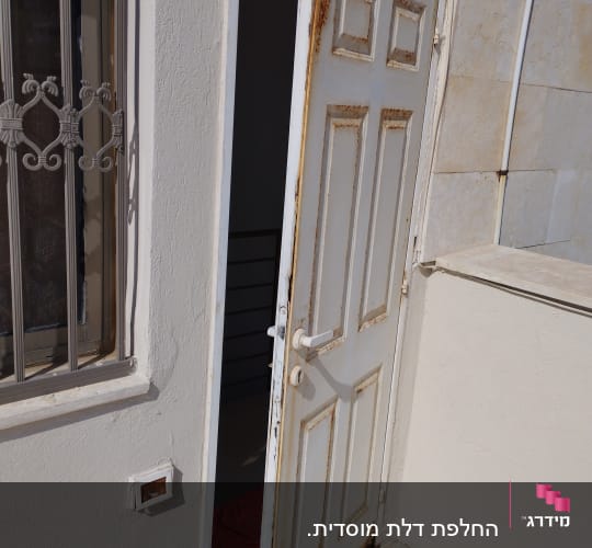 דלת לבנה עם חלודה פתוחה למחצה